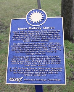 Bronze plaque with sun emblem at the top and description of Essex Railway Station below