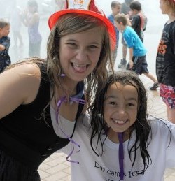 Two girls, one wearing a junior firefighter helmet